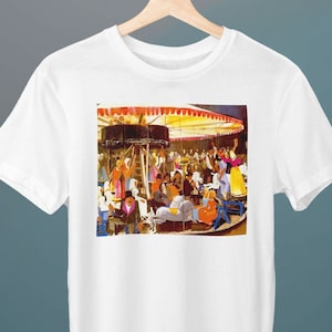 Puede incluir: Una camiseta blanca con una pintura colorida de un carrusel con personas montando en él. El carrusel está bajo un dosel a rayas rojas y amarillas.
