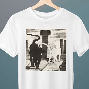 以下が含まれることがあります： 白地に黒と白の猫のイラストが描かれたTシャツ。猫は互いに向き合っていて、一匹は黒、もう一匹は白。イラストはヴィンテージスタイルです。