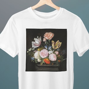 May include: A white t-shirt with a print of a still life painting featuring a variety of flowers in a vase. The flowers are pink, white, yellow, orange, and red.