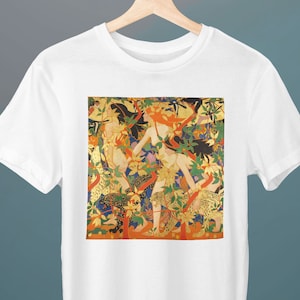 Peut inclure: T-shirt blanc avec un imprimé coloré d'une peinture représentant trois personnages dans un décor forestier. Les personnages sont entourés d'une végétation luxuriante, de fleurs et d'oiseaux. L'arrière-plan est une toile de couleur or.