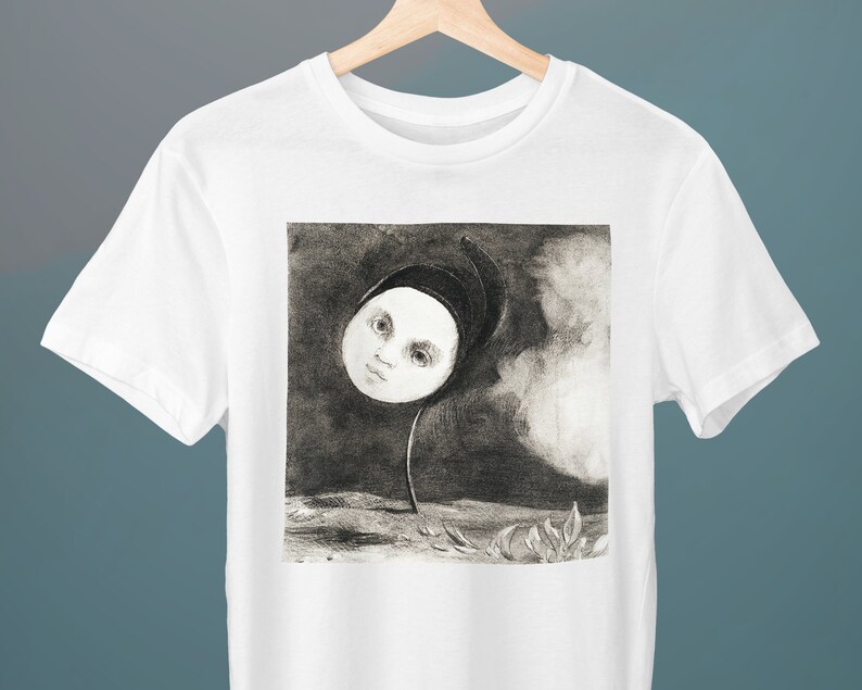 May include: A white t-shirt with a black and white illustration of a face with a hooded head on a stem, resembling a flower.