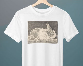 May include: White t-shirt with a black and white illustration of a rabbit lying down.