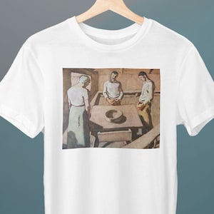 May include: A white t-shirt with a painting of three people standing around a table. The people are wearing simple clothing and the painting is in a muted color palette.