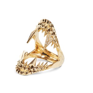Könnte beinhalten: Ein goldener Ring mit einem detaillierten Design eines Haimauls mit scharfen Zähnen. Der Ring ist mit kleinen Diamanten besetzt.