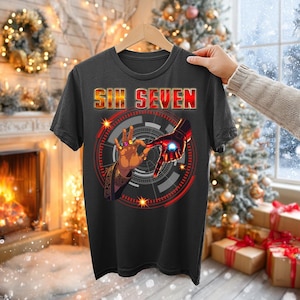 Könnte beinhalten: Dunkelgraues T-Shirt mit dem Text "SIX SEVEN" in Orange und Rot. Das Shirt zeigt eine Grafik von zwei Händen, eine mit goldenen Ringen und die andere eine rote und goldene Roboterhand, mit einem roten und grauen kreisförmigen Design.