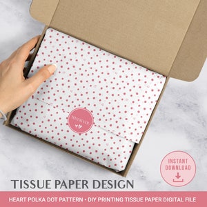 Könnte beinhalten: Ein weißes Seidenpapier mit einem rosa Tupfenmuster und kleinen rosa Herzen. Das Seidenpapier ist gefaltet und in einer braunen Pappbox verpackt. Der Text "THANK YOU" ist auf einem rosa runden Aufkleber auf dem Seidenpapier gedruckt.
