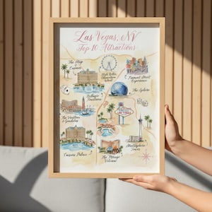 May include: A framed watercolor map of Las Vegas, Nevada, showcasing the top 10 attractions. The map includes illustrations of casinos, the High Roller, the Sphere, and the Stratosphere Tower. The title "Las Vegas, NV Top 10 Attractions" is written in cursive.