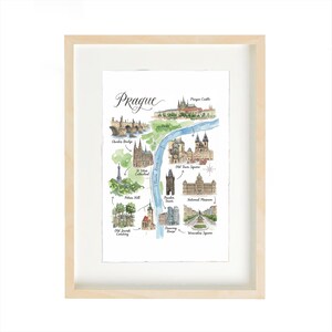 Pode incluir: Mapa em aquarela emoldurado de Praga, República Tcheca, com marcos como a Ponte Carlos e o Castelo de Praga. A obra de arte é apresentada em uma moldura de madeira clara. O mapa é pintado à mão com uma paleta de cores suaves.