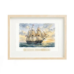 May include: Watercolor painting of a tall ship sailing on the ocean, framed in a light wood frame. The ship has multiple masts and sails, with American flags. The text at the bottom reads "USS Constitution - American Hero, War of 1812."