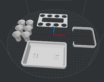May include: A collection of white 3D-printed components, including six small cups, a rectangular tray with two raised sections, a slotted rectangular piece, and a curved handle-like structure. The items are arranged on a dark surface.