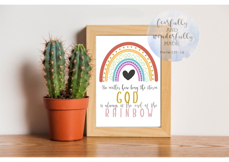 May include: A framed print with a colorful rainbow design and the text "No matter how long the storm GOD is always at the end of the RAINBOW." A small cactus in a terracotta pot sits to the left of the frame.