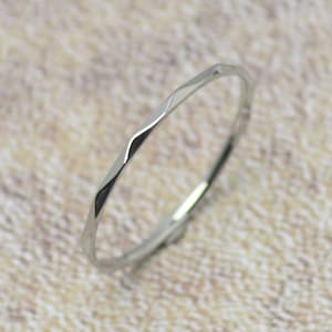 Könnte beinhalten: Ein dünner Silberring mit gehämmerter Textur. Der Ring ist schlicht und zart und wäre ein tolles Schmuckstück für jeden Tag.