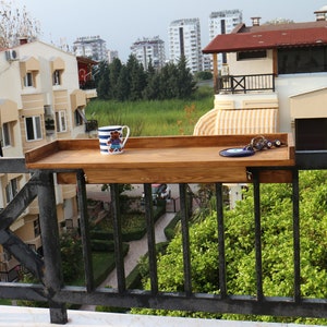 A wooden balcony bar table has a 3 cm high frame on the sides that prevents the objects on it from falling down. The wooden wings  attached under the table are fixed to your railing, with 2 hand-tight nuts.