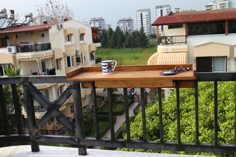 A wooden balcony bar table has a 3 cm high frame on the sides that prevents the objects on it from falling down. The wooden wings  attached under the table are fixed to your railing, with 2 hand-tight nuts.