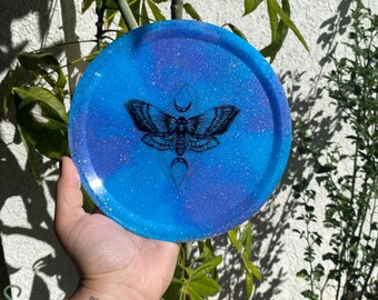 May include: A blue and purple glitter resin coaster with a black moth and crescent moon design.