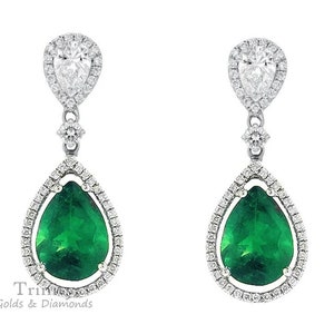 May include: A pair of pear-shaped emerald and diamond drop earrings. The emeralds are a vibrant green and are surrounded by a halo of smaller diamonds. The earrings are suspended from a delicate chain with a small diamond accent.