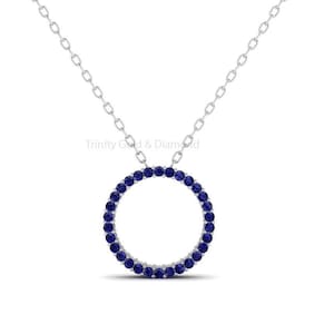 May include: A silver chain necklace with a circle pendant made of small blue sapphires.