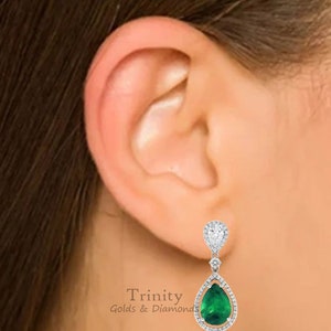 May include: A pair of pear-shaped emerald and diamond drop earrings. The earrings are set in white gold and feature a pear-shaped emerald surrounded by a halo of diamonds. Trinity Golds & Diamonds.