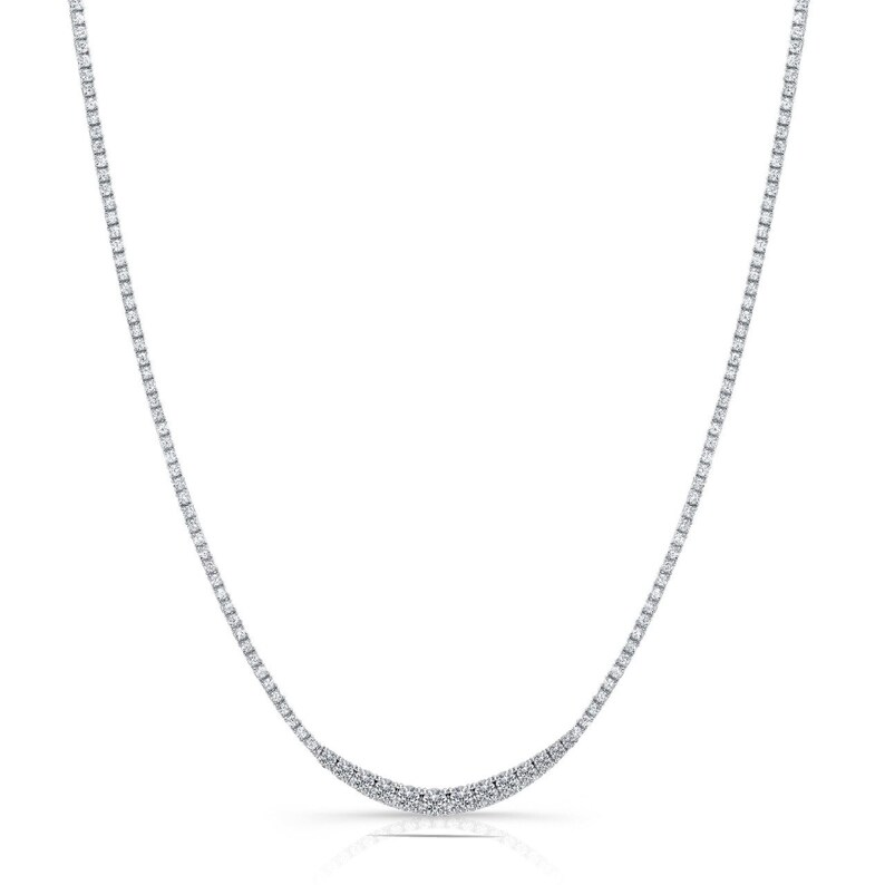 K&ouml;nnte beinhalten: Eine zarte silberne Halskette mit einem geschwungenen Design, die mit einer Reihe kleiner, funkelnder Diamanten besetzt ist.