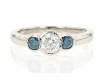 May include: A white gold ring with a round center diamond and two smaller blue diamonds on either side.
