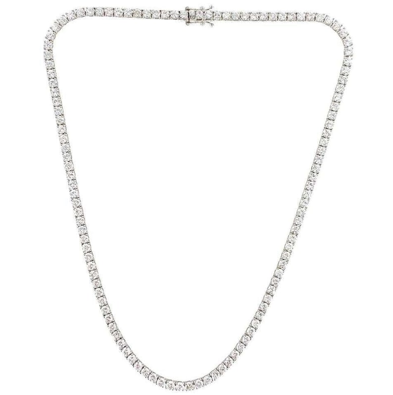 Puede incluir: Un collar de cadena de tenis plateado con una fila de piedras de circonita c&uacute;bica transparentes.