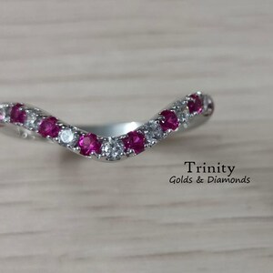 Peut inclure: Une bague en argent avec un design incurvé, sertie de rubis rouges et de diamants blancs alternés.