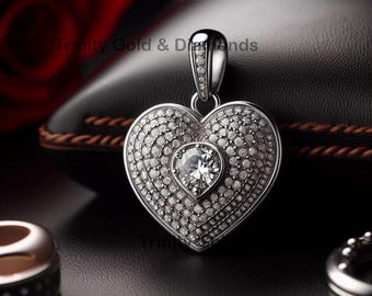 May include: A silver heart-shaped pendant with a large clear gemstone in the center, surrounded by smaller clear gemstones. The pendant is on a black background.