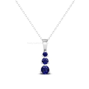 May include: A silver necklace with a pendant featuring three blue sapphires arranged vertically.