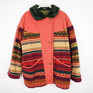 Könnte beinhalten: Ein vintage korallenfarbener Mantel mit einem grünen Kunstfellkragen. Der Mantel hat ein gemustertes Design in Rot, Beige, Grün und Marineblau. Er hat zwei Taschen und Holzknöpfe.