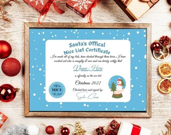 May include: A framed "Santa's Official Nice List Certificate" with a blue background and white snowflakes. The certificate includes text fields for a name and the year 2022, along with a snow globe graphic. Christmas decorations surround the frame.