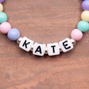 May include: A colorful beaded bracelet with the name "KATE" spelled out in white letter beads.