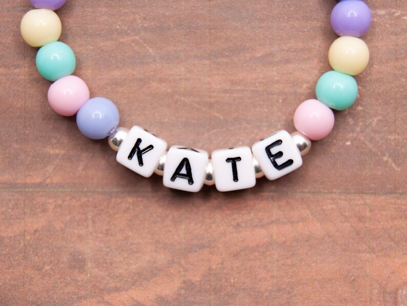 May include: A colorful beaded bracelet with the name "KATE" spelled out in white letter beads.