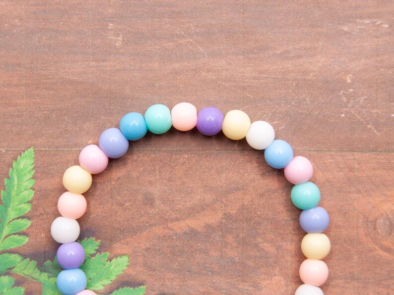 May include: A pastel-colored beaded bracelet with alternating shades of light blue, pink, yellow, and purple.