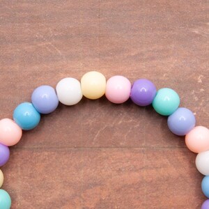 May include: A pastel-colored beaded bracelet with alternating colors of light blue, pink, white, yellow, and purple.