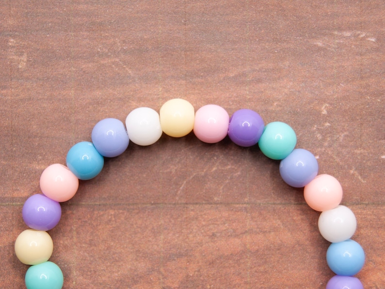 May include: A pastel-colored beaded bracelet with alternating colors of light blue, pink, white, yellow, and purple.