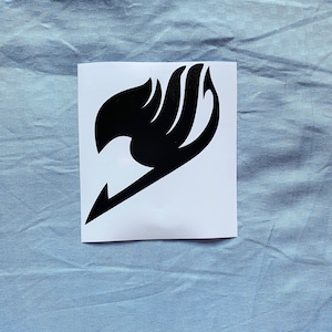 Könnte beinhalten: Schwarz-weißer Vinyl-Aufkleber mit dem Fairy Tail-Logo. Das Logo ist eine stilisierte Darstellung einer Hand mit Flammen.