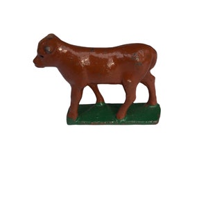 May include: A brown cast iron figurine of a calf standing on a green base.