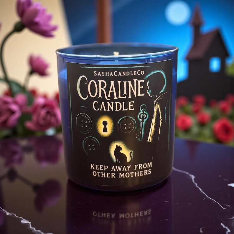 May include: A blue glass candle with a black label featuring the text "Coraline Candle" and illustrations of buttons, a key, and a cat. The candle has the text "Keep Away From Other Mothers".