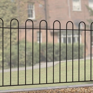 May include: A black metal fence with a decorative design. The fence features vertical bars and arched tops, with a small ball finial on the posts. The fence is set against a blurred background of greenery and a building.