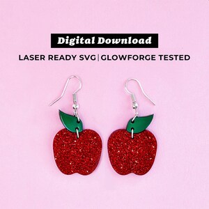 May include: A pair of apple-shaped earrings with red glitter and green leaf accents. The earrings have silver-colored hooks. The image also includes the text "Digital Download" and "LASER READY SVG | GLOWFORGE TESTED".