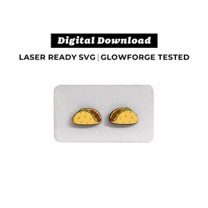 May include: Two yellow taco earrings with brown filling and green lettuce. The earrings are on a white background.