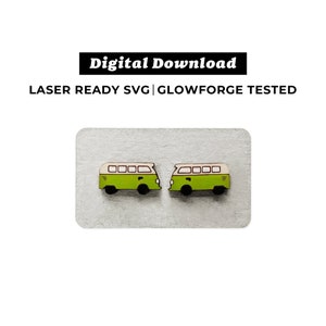 May include: Two green and white wooden camper van earrings. The vans have a white roof and windows, and black wheels.