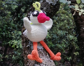 May include: A white crocheted bird with a pink beak and black eyes sits on a tree branch. The bird has orange legs and a yellow crest.