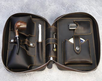 May include: A brown leather travel case with multiple pockets and compartments. The case is open to reveal a pipe, a small tool, and a small container.
