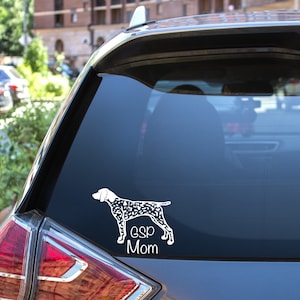 May include: A white car with a black and white dog silhouette sticker on the back window. The sticker says "ESP Mom".