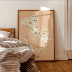 May include: A framed wall art print featuring a stylized map of Italy on a light peach background. The map includes small illustrations of landmarks, food, and regional icons across the country, with the word Italy written in cursive at the bottom.
