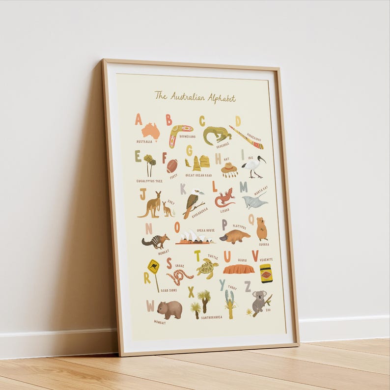 Puede incluir: Un p&oacute;ster educativo enmarcado titulado The Australian Alphabet que presenta ilustraciones para cada letra de la A a la Z, incluyendo animales, monumentos y objetos culturales en tonos tierra apagados sobre un fondo crema, en un marco de madera clara.