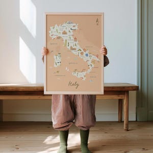 May include: A framed wall art print featuring a light peach-colored map of Italy. The map includes illustrated icons of landmarks, food, and nature across the country, with the word Italy written in a cursive script at the bottom center.