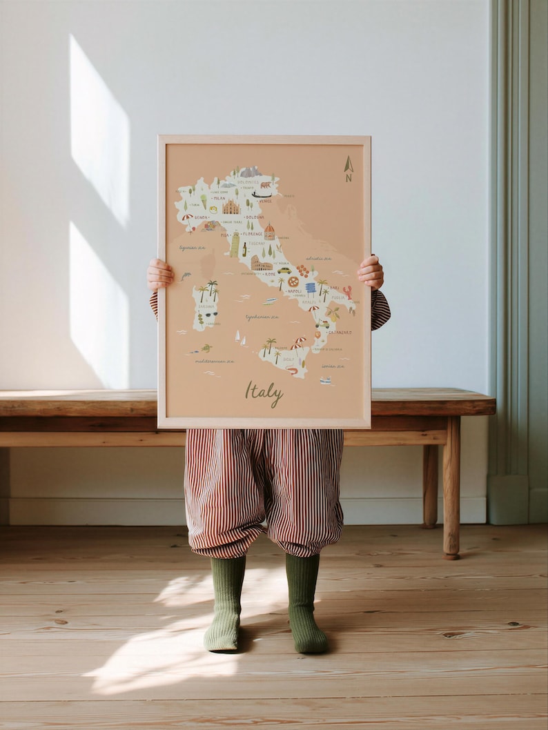 May include: A framed wall art print featuring a light peach-colored map of Italy. The map includes illustrated icons of landmarks, food, and nature across the country, with the word Italy written in a cursive script at the bottom center.