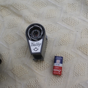 Può includere: Un proiettore per pellicole in bianco e nero del marchio Tully con un obiettivo argentato e una batteria nera. La batteria è una batteria ASI da 1,5 V, 01M.